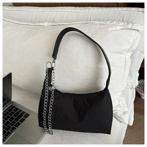 Détail du sac baguette en nylon noir avec chaîne en métal et bandoulière en cuir