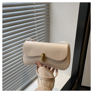 Close-up of minimalist beige square bag with elegant gold-tone oval metal buckle detail