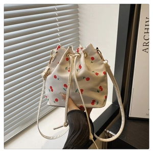 Macro shot of white drawstring bucket bag with cherry print and golden metal clasp