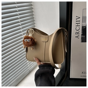 Detail of khaki shoulder bag with FASHION label and fluffy monster charm decoration