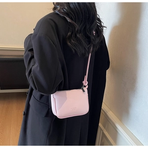 Detail of pink lychee leather crossbody bag featuring knot strap and brand logo