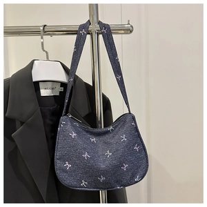 Detail of dark blue denim shoulder bag featuring cute pink and white bow patterns