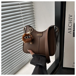Detail of dark brown leather bucket bag with fashion plaque and plush glasses pendant