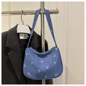 Detail of blue denim shoulder bag featuring delicate colorful butterfly bow prints