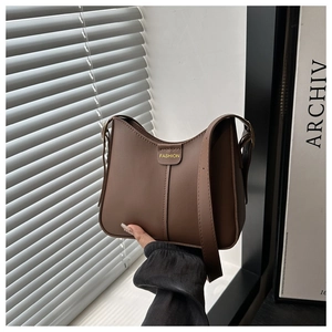 Close-up of dark brown leather bucket bag featuring a vertical seam and embossed FASHION tab