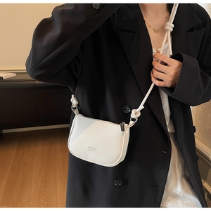 Detail of white crossbody bag featuring lychee grain texture and chunky rope strap knots