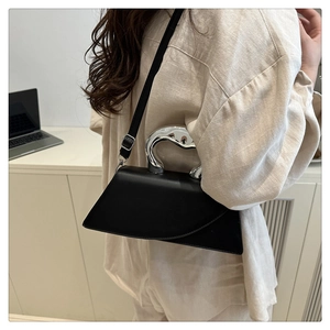 Dettaglio della borsa a trapezio nera minimalista con manico in metallo argentato unico