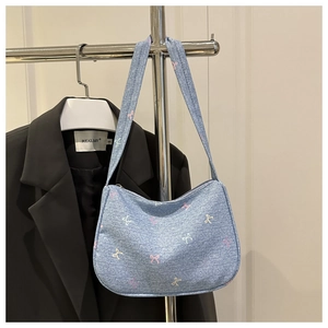 Detailed close-up of light blue denim bag with colorful embroidered mini bow patterns