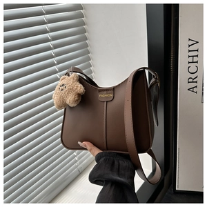Detail of coffee brown crossbody bag with FASHION text and plush bear charm