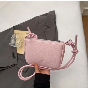 Detail of pink lychee leather crossbody bag with silver zipper and knotted cord strap