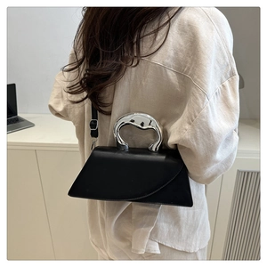Dettaglio borsa in pelle nera con manico in argento fuso e tracolla sottile regolabile