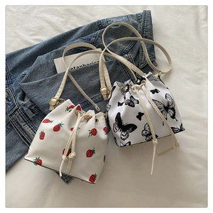 Detail of small bucket bags with strawberry and butterfly prints on soft white faux leather