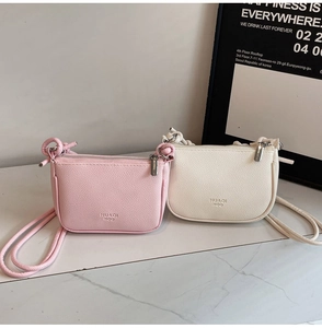 Detail view of pink and white pebbled leather crescent bags with knotted strap accents