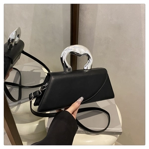 Dettaglio della borsa a trapezio in pelle nera con manico scultoreo in metallo argento