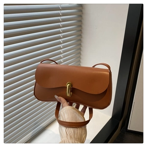 Detailed view of caramel leather shoulder bag with elegant gold oval twist lock closure