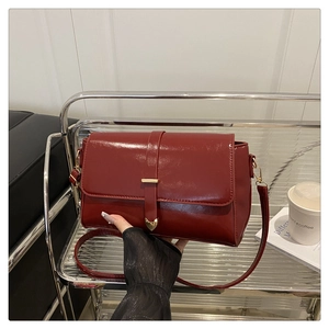 Close-up of deep red leather crossbody bag featuring gold cat-ear metal magnetic buckle
