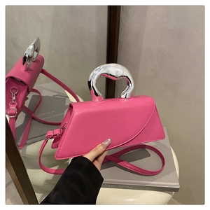 Dettaglio borsa a trapezio rosa con manico curvo in argento e riflesso a specchio