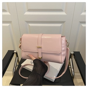 Detail of pink faux leather crossbody bag with heart-shaped buckle and gold hooks