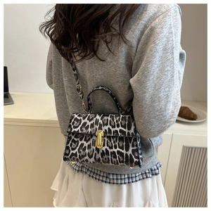 Detailed back view of a leopard print handbag with metal twist lock and adjustable strap