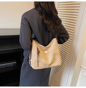Détail du grand sac hobo beige avec décor en triangle métallique et fermeture éclair