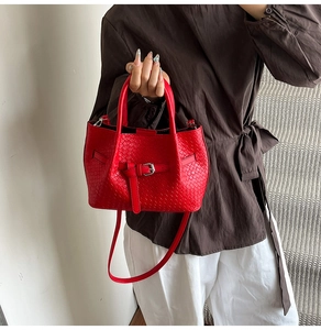 Vue détaillée du sac cabas rouge tressé avec boucle et bandoulière réglable pratique