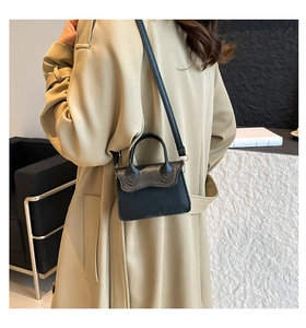 Détail du petit sac bandoulière noir en cuir grainé avec rabat au design ondulé