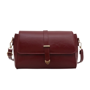 Minimalist deep red crossbody bag with sleek leather texture and gold buckle accents