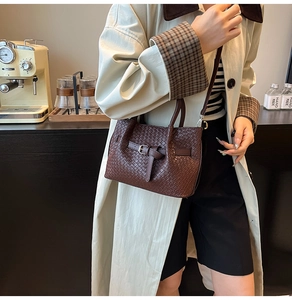 Detail of dark brown woven handbag with buckle strap and silver metallic hardware
