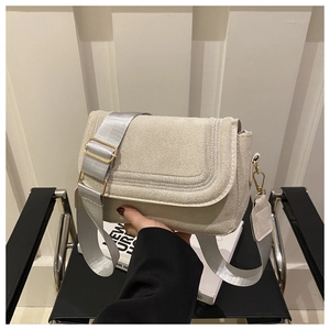 Detail of creamy suede saddle bag with wide nylon strap and golden metal buckles