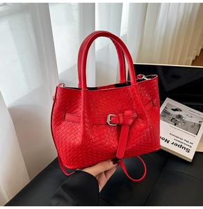 Détail du sac seau tressé rouge avec boucle en cuir et bandoulière amovible