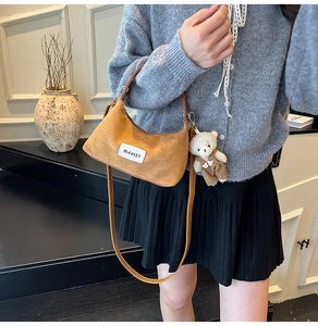 Détail d'un sac en daim marron avec étiquette blanche et charmant petit ours peluche
