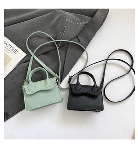 Détail de mini sacs en cuir grainé vert menthe et noir sur un fond de veste grise