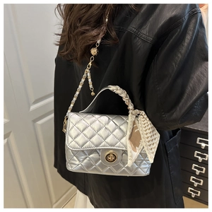 Detailed view of silver quilted crossbody bag with silk scarf handle and gold twist lock