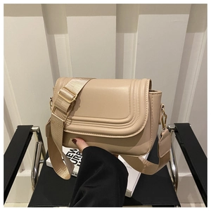Close-up of beige suede saddle bag featuring decorative stitching and gold metal hardware