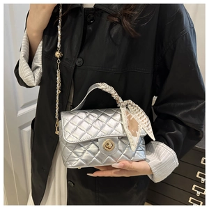 Detail of silver quilted crossbody bag with golden twist lock and silk scarf handle