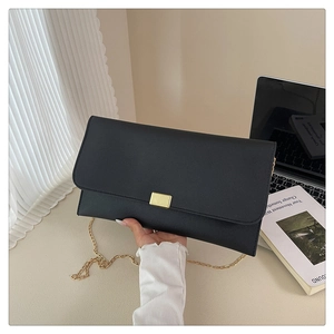 Close-up of black envelope chain bag with gold rectangular metal clasp and cross-grain leather