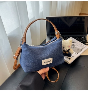 Détail du sac à bandoulière en denim avec anses en cuir brun et breloque ours en peluche