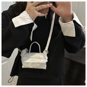 Close-up of a white ballet-style crossbody bag with lace trim and ribbon bow detail