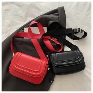 Detail of red and black faux suede saddle bags with wide adjustable nylon straps