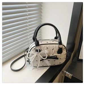 Détail du sac blanc plissé avec motifs nœuds noirs, dentelle et perles nacrées