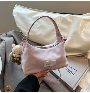 Détail du sac à main en daim rose avec charme ours et écusson logo décoratif