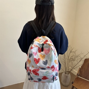 White nylon backpack with colorful heart print for women, adjustable straps shown on model