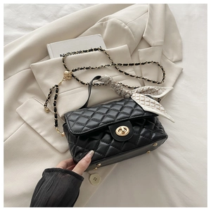 Detail of black quilted crossbody bag with golden twist lock and silk scarf handle