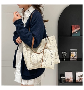 Detailed shot of large cream tote bag with YADIER print and brown leather straps on model