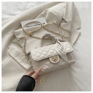 Detail of cream quilted crossbody bag with gold twist lock and printed scarf handle