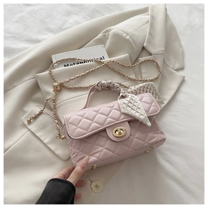 Close-up of pink quilted bag with gold hardware, metal feet and printed silk scarf handle