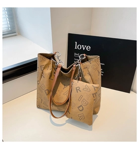 Detail of brown tote bag with letter pattern, chain strap and matching small pouch