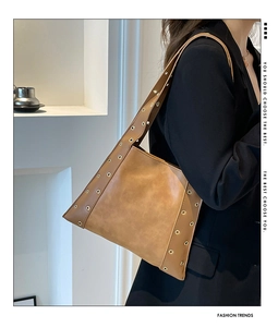 Détail du sac fourre-tout en similicuir marron avec œillets métalliques dorés et bandoulière