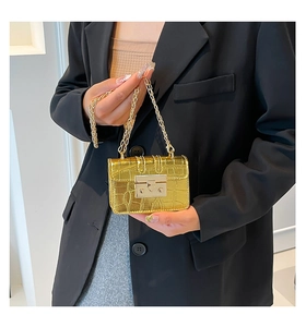 Dettaglio mini borsa dorata con trama a coccodrillo e tracolla a catena indossata