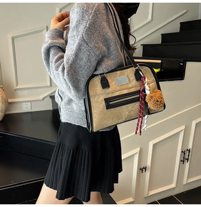 Détail du sac bandoulière kaki avec bordures noires et accessoire porte-clés ours